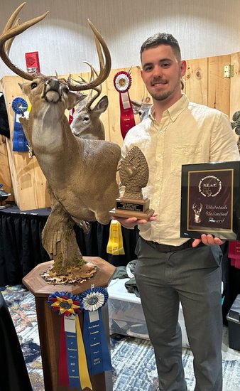 Taxidermist with a whitetail buck mount and Whitetails Unlimited award